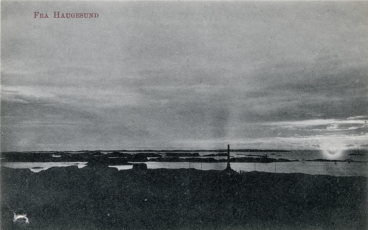 Postkort med bilde av Haralstøtta og havet utenfor. Det er kveldsstemning med landskap i relieff, mye himmel og solnedgang.