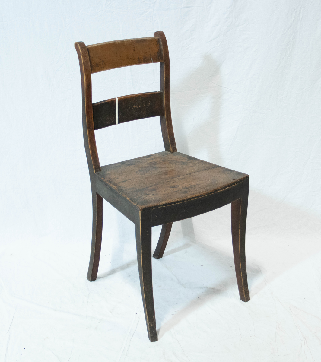 Stol av tre. Stolen har fire sabelformede ben og glatt sarg. Setet er trapeslignende med horisontalt buet fremkant.  Stolen har S-svungne ryggstaver forbundet med to glatte horisontale bretter.