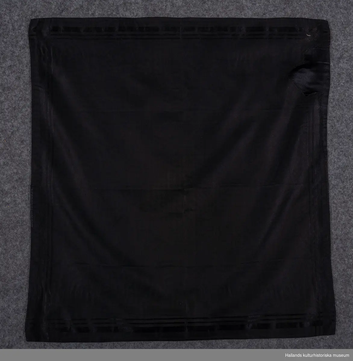 Huvudduk av svart siden med sammansatt bindning i kypertbotten och med satinränder i kanterna.