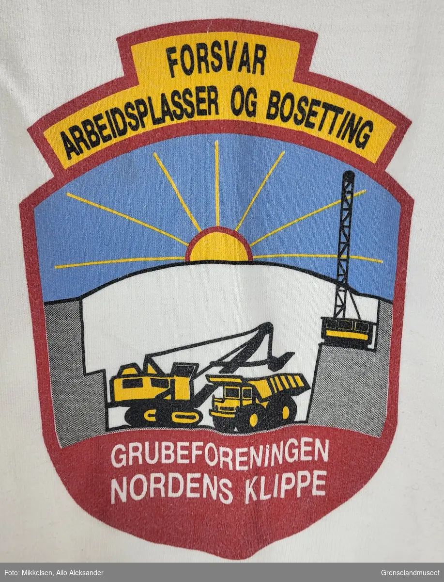 Gjenstanden er en hvit skjorte med logoen til Grubeforeningen Nordens Klippe på forsiden og teksten "Grubeforeningen Nordens Klippe" på ryggen. 