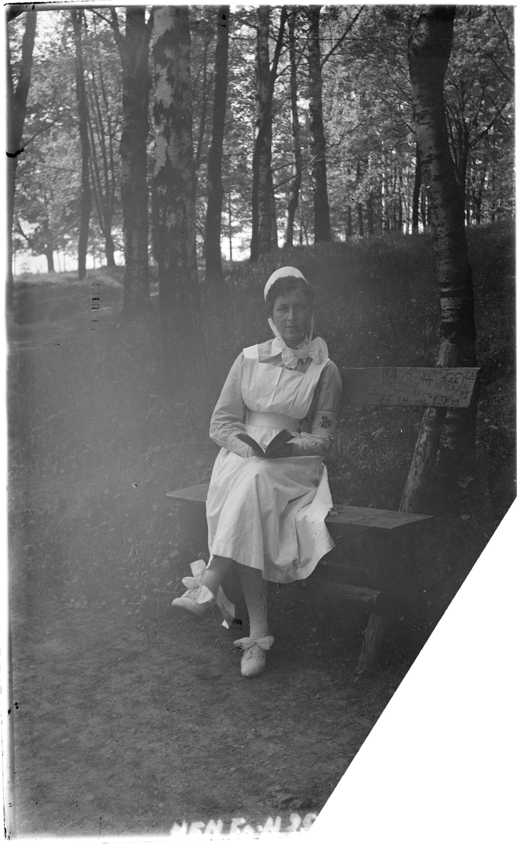Portrett
1 sykesøster i uniform på en benk i parken.
