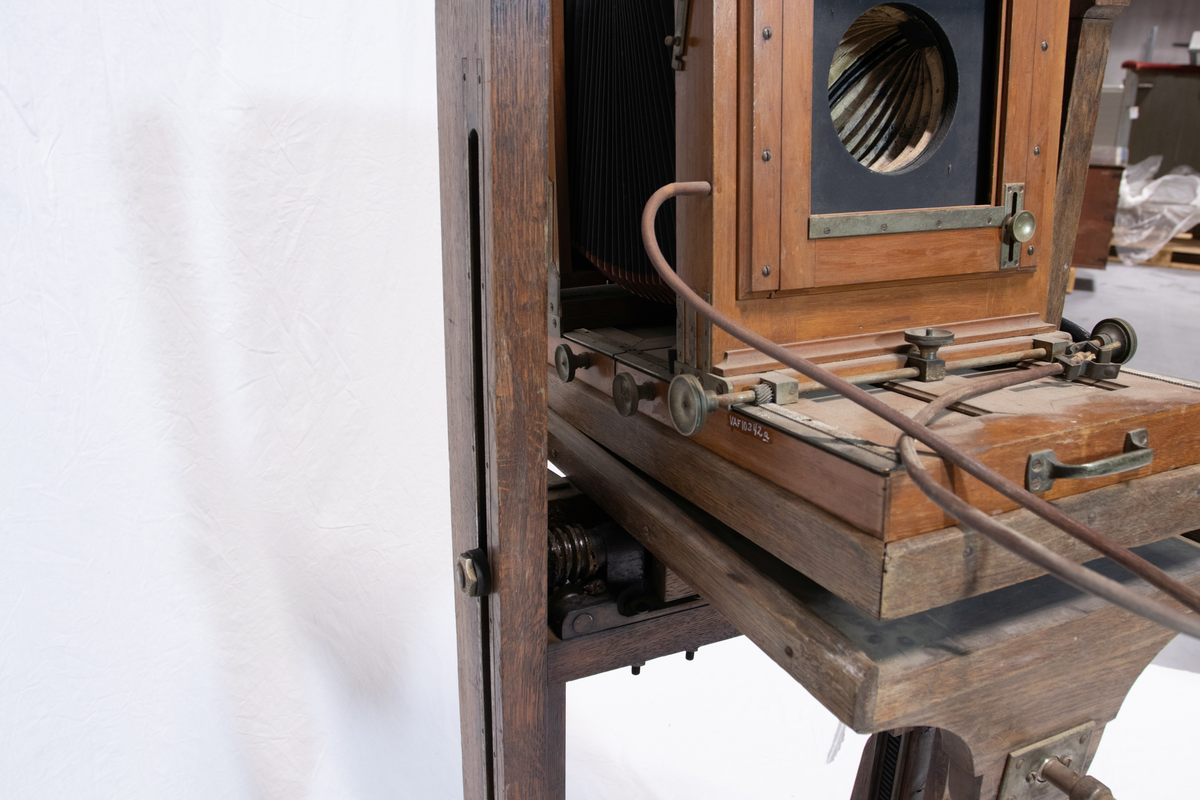 Fotografiapparat på stativ med  gjengeverk og drivhjul drevet av en sveis. Stativet har en vippeplate forregulering av fotokasse.