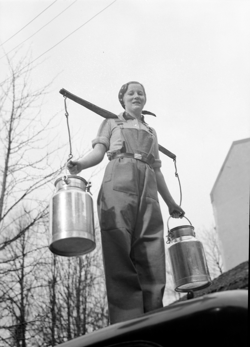 Kvinne bærer melkepann med vassåk