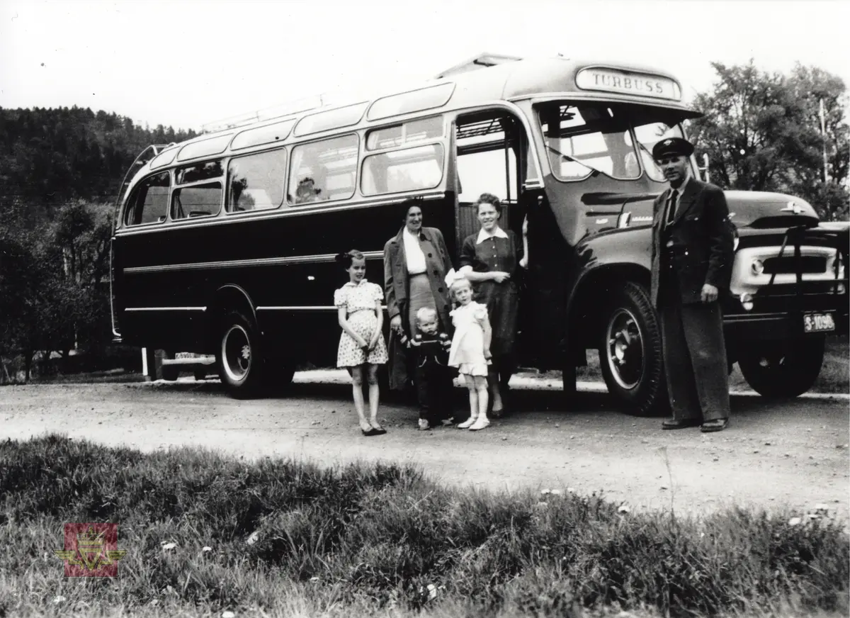Ny buss til Firda Billag av merke International, henta år 1953 eller 1954 i Søgne i Vest Agder.

Sjåfør Sigmund Hegheim har med seg familien. 

Bussen har kjennetikn S-1090  som truleg er eit prøvekjenneteikn.