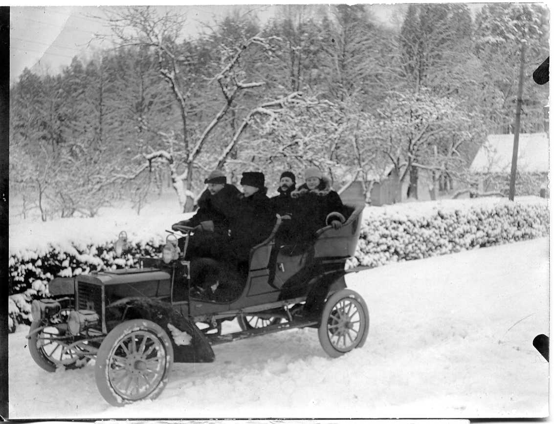 Fyra vinterklädda män i en öppen bil i ett vinterlandskap.