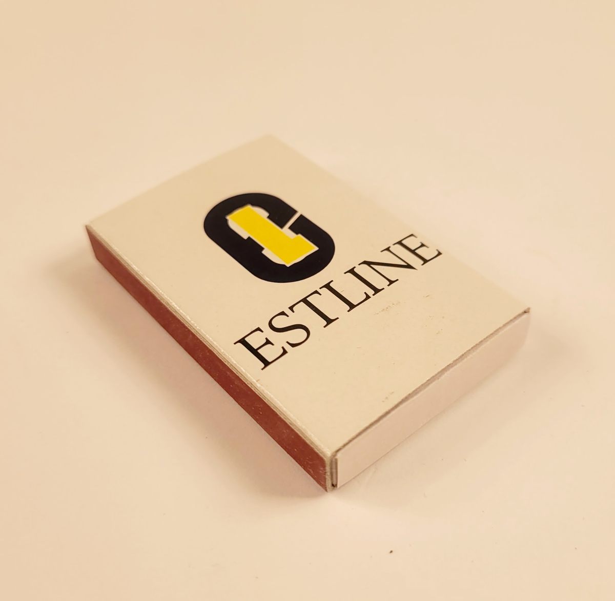Vit tändsticksask med rederi Estlines logotyp för åren 1990-1994.