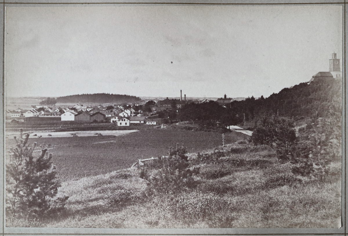 Ett vykort som är inklistrat i vykortsalbum nr. EM6774:1. Vykortet har motiv av Enköping fotograferat från Fannaområdet.