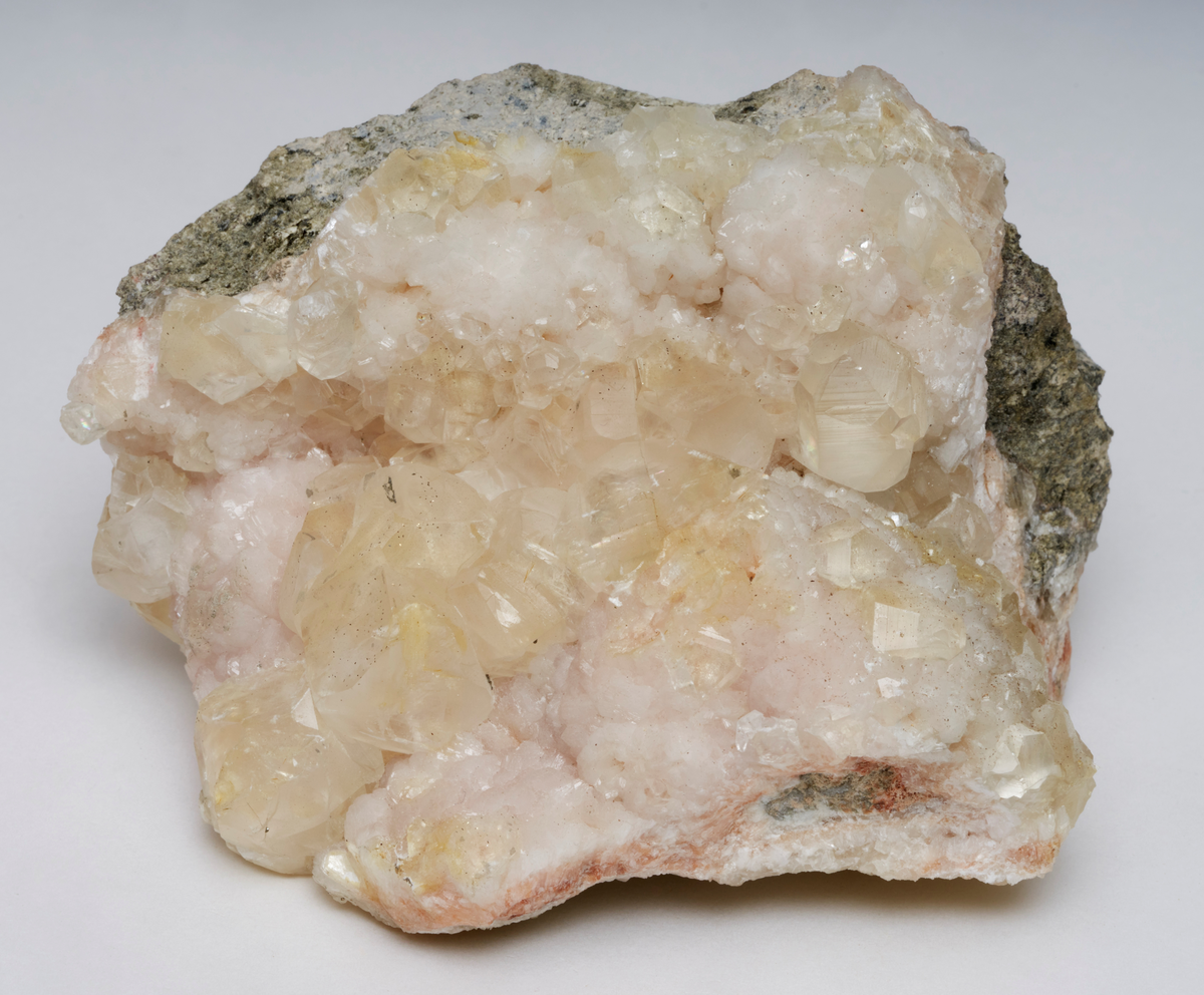 Kalsitt på stilbitt. Gulhvite og gjennomsiktige krystaller av kalkspat sammen med grålige og tette kuleformede krystallaggregater av stilbitt.
