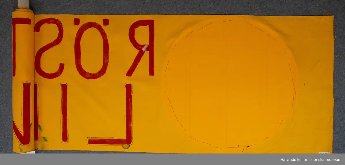 Banderoll av gult bomullstyg med antikärnkraftssymboler, (den glada solen) i wellpapp. Röd text: "RÖSTA NEJ LINJE 3".