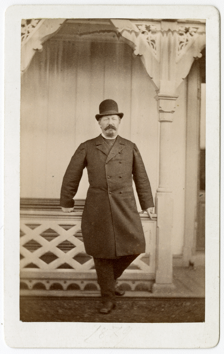 Foto av Kommandant Nils Juell som lener seg mot gelender på Dal gård i 1879.