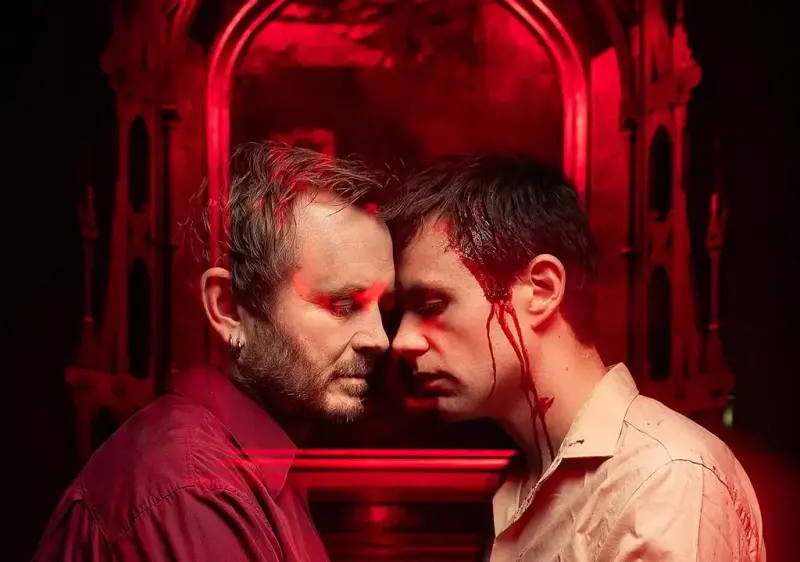 To menn står mot hverandre med panner som berører hverandre, rødt lys i bakgrunnen.