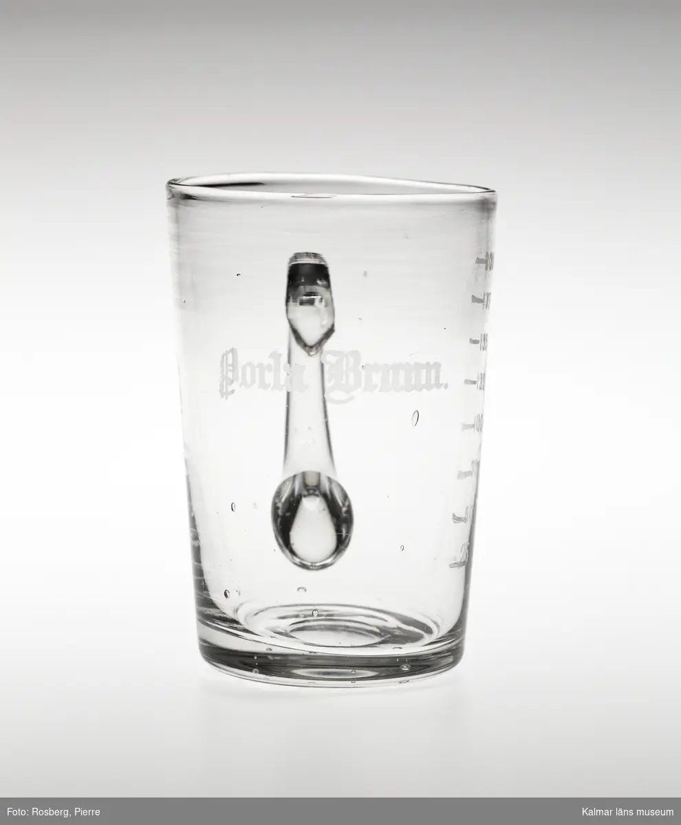 KLM 28155:2. Hankglas, av glas. Glaset är avsmalnande neråt med lodrät grepe. Slipad text, Porla Brunn och måttsticka för, 24, 50, 75, 100, 125, 150, 175, 200.