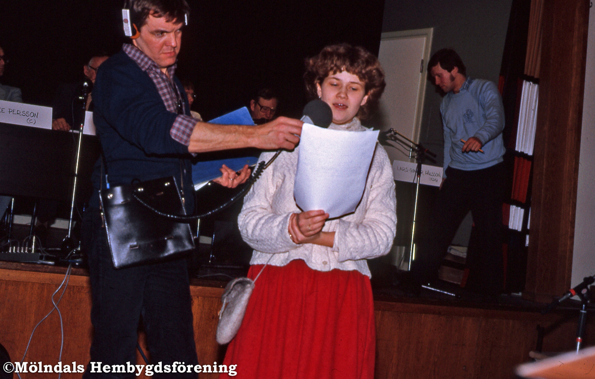 Debatt angående Fässbergsdalen i Mölndals Folkets hus i januari 1985. Helena Rödholm läser ett upprop från aktionsgruppen "Rädda Fässbergsdalen". Till vänster lokalradions Jakob Wennerberg.