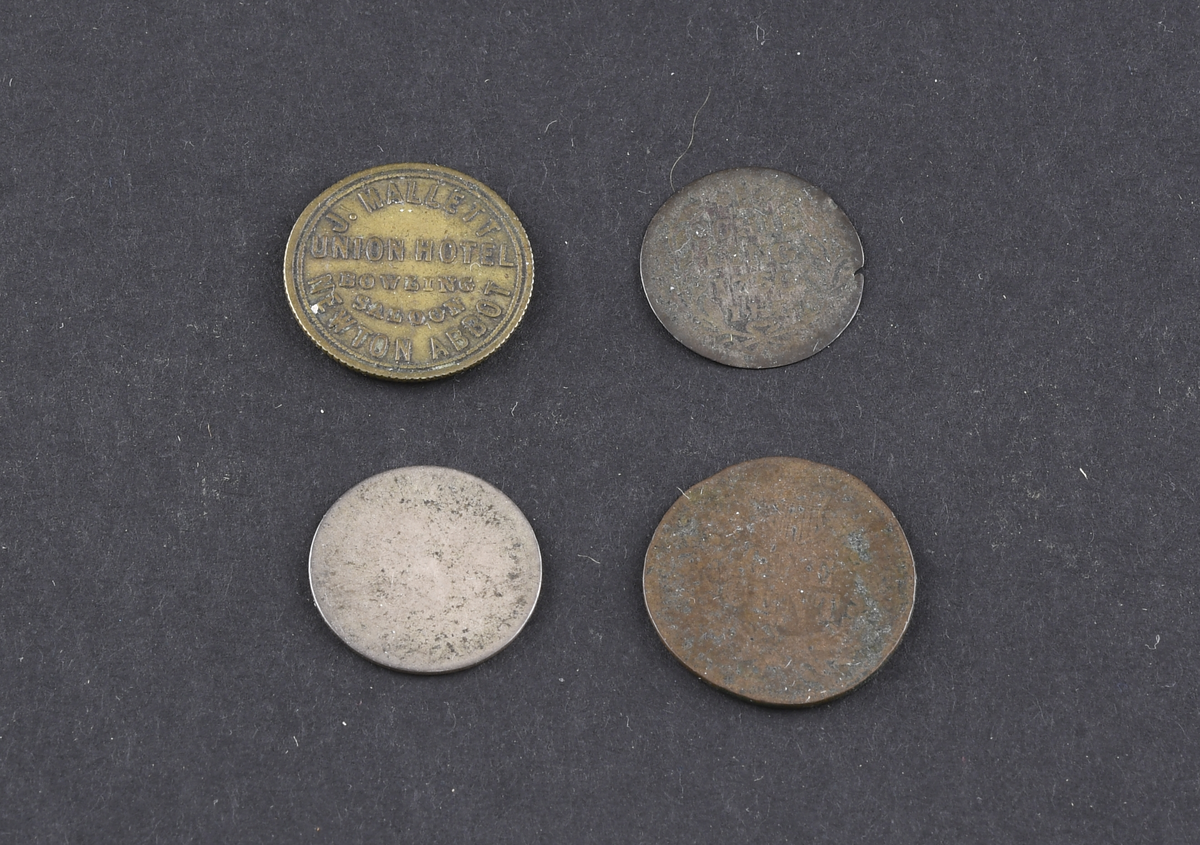 Fire mynter og polletter i varierende størrelse og tilstand. Myntene er fra USA, Tyskland og England. Myntene og polettene var oppbevart i en liten papirpose.