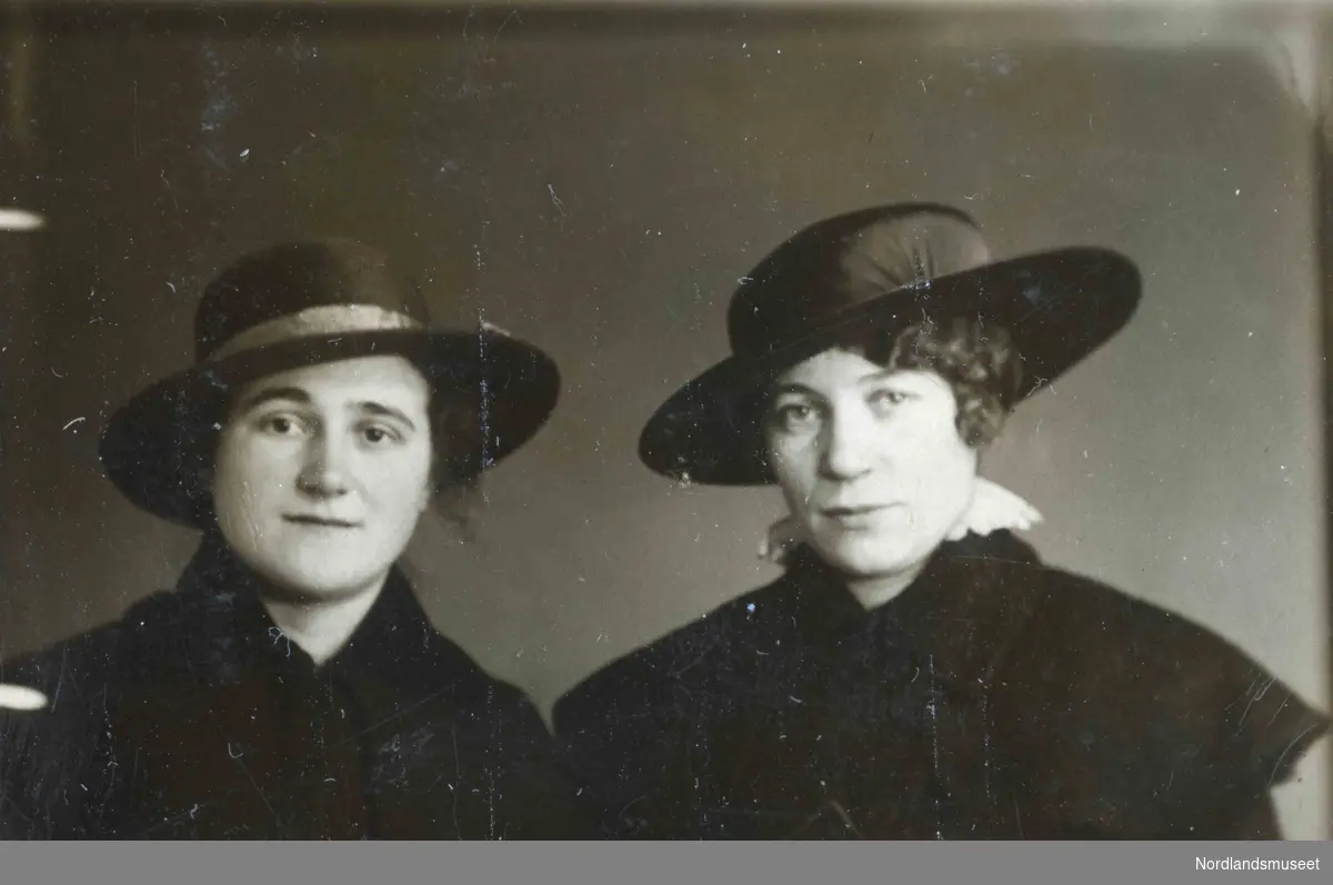 To kvinner med mørke klær og hatt.