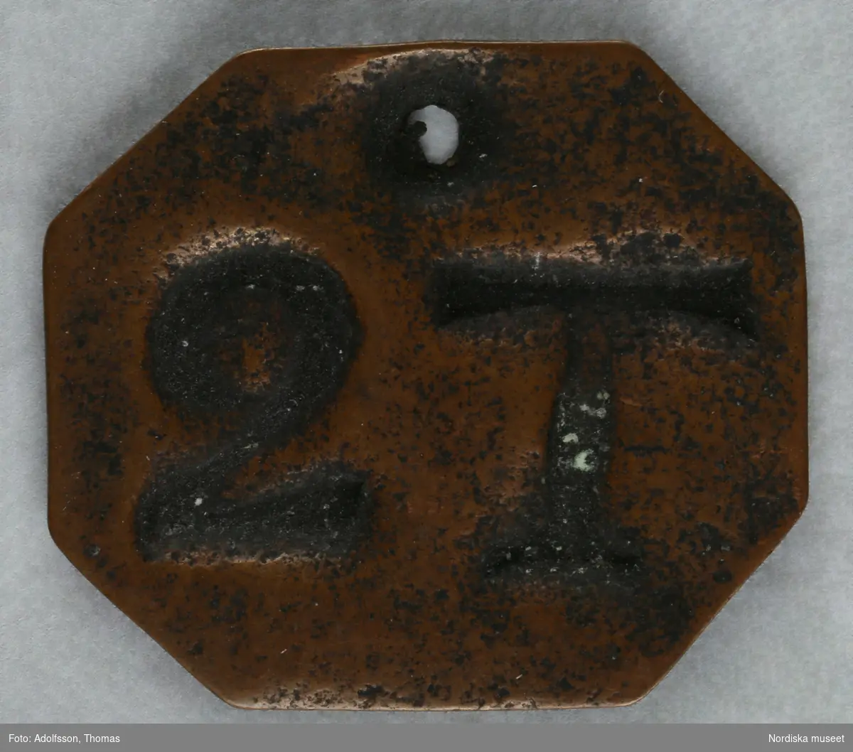 Pollett, av koppar, fyrkantig, hål, präglad text: "2 T".