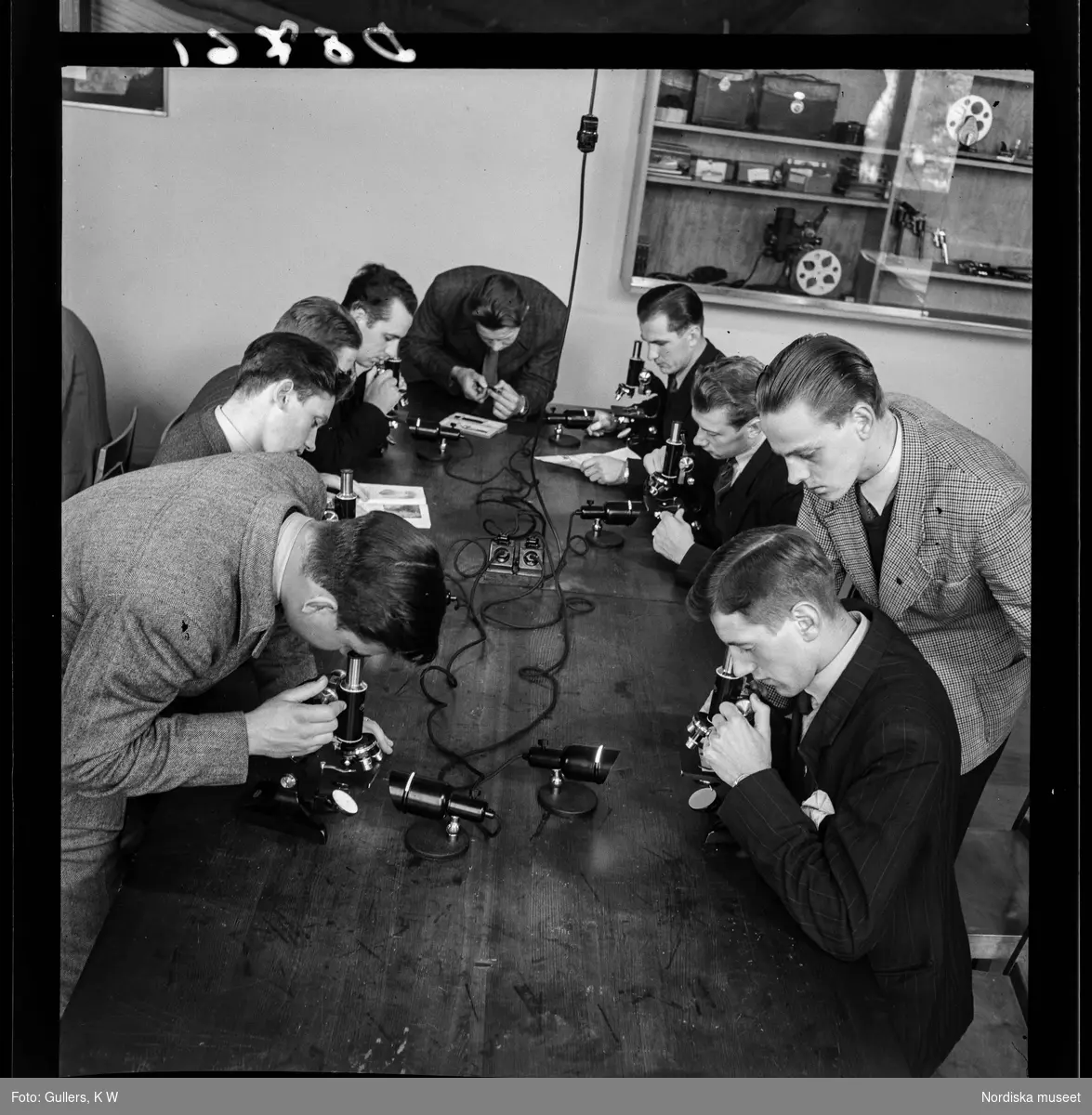 534 Polisskolan. Elever sitter runt ett bord och studerar något i mikroskop.