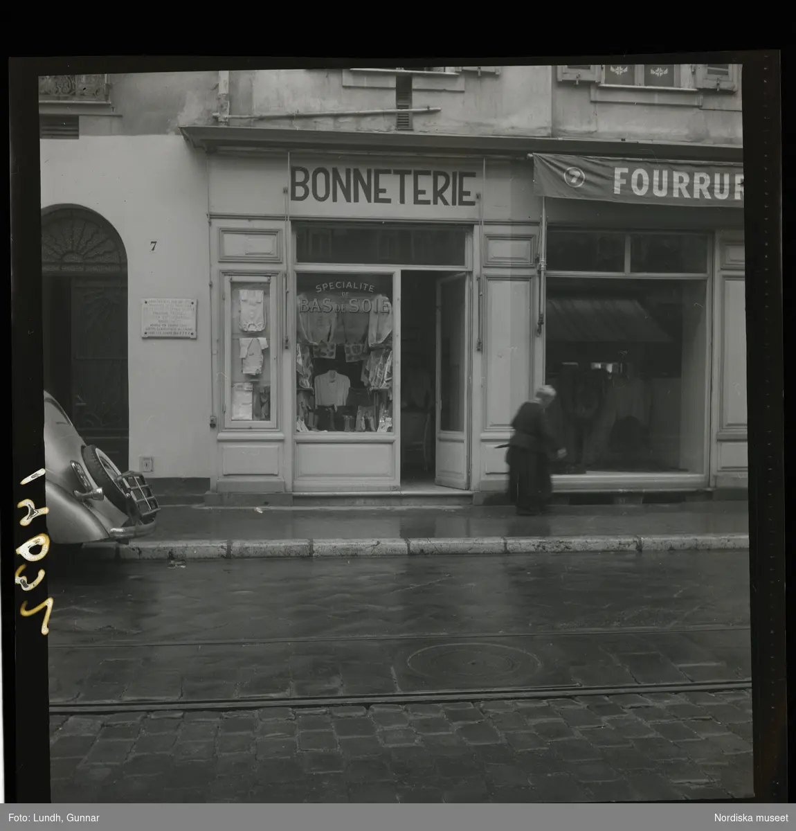 1950. Frankrike. En kvinna gående förbi en trikåbutik
