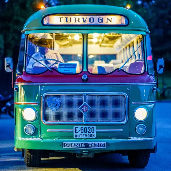 Fronten på en veteranbuss med skumrende kveldslys og sjåfør i sjåførsetet