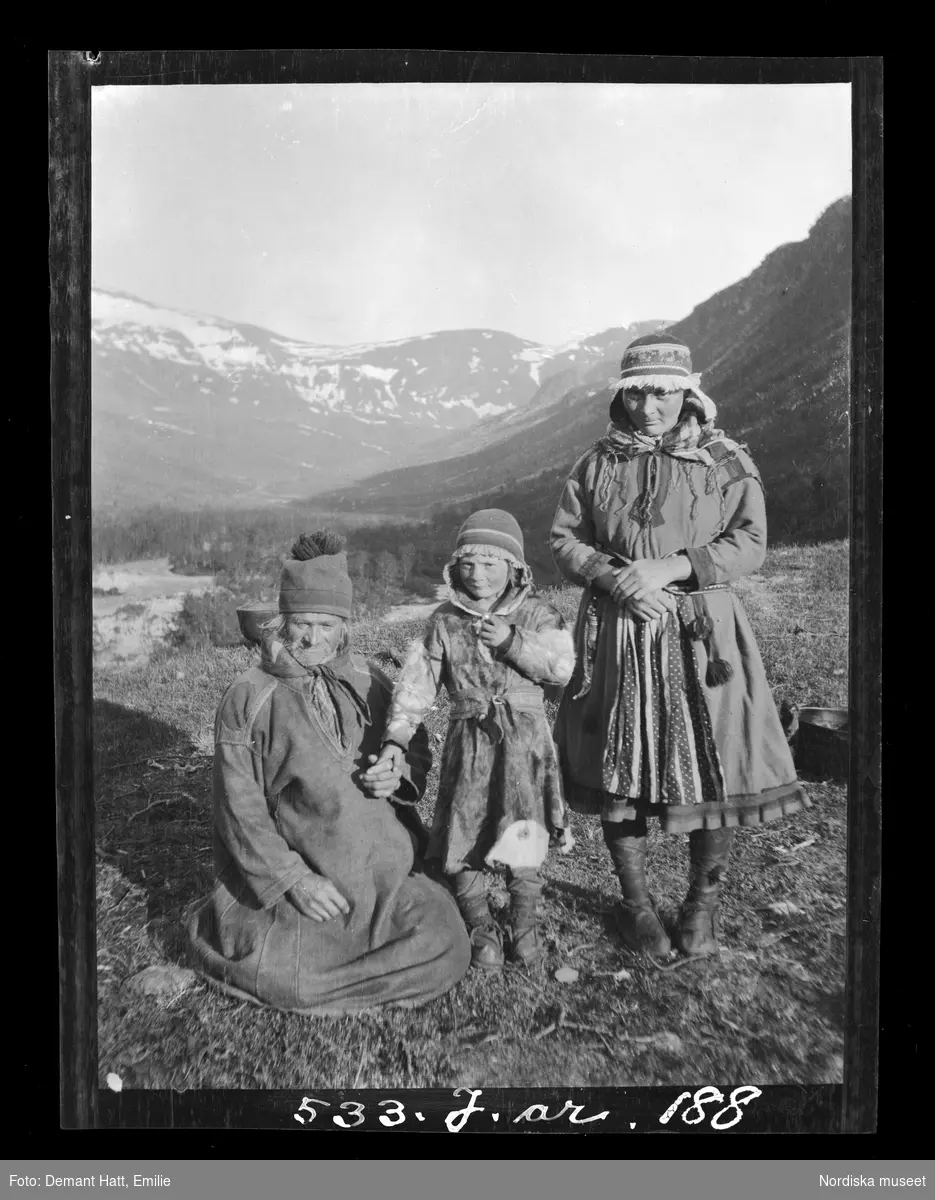 En man, Andaras Omma, med två döttrar, den yngsta vid namn Ingas (Ellis). Tromsödalen. Bilden ingår i en serie fotografier tagna av Emilie Demant Hatt i Sapmi mellan åren 1907 och 1916.