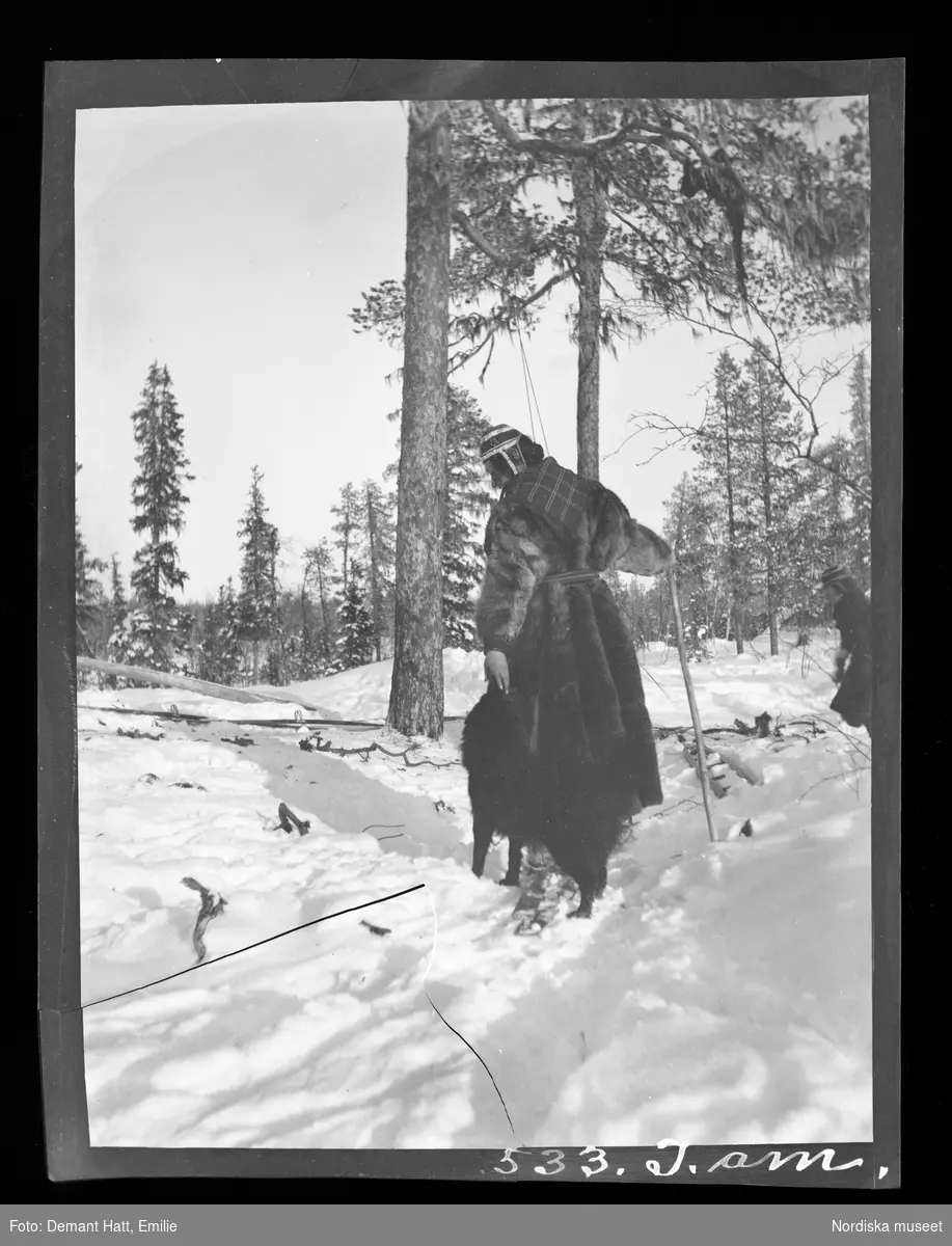 Kvinna, Emilie Demant Hatt, leker med hunden Rill i snön. Troligen under höstflyttningen vid Laimo. Bilden ingår i en serie fotografier tagna av Emilie Demant Hatt i Sapmi mellan åren 1907 och 1916.