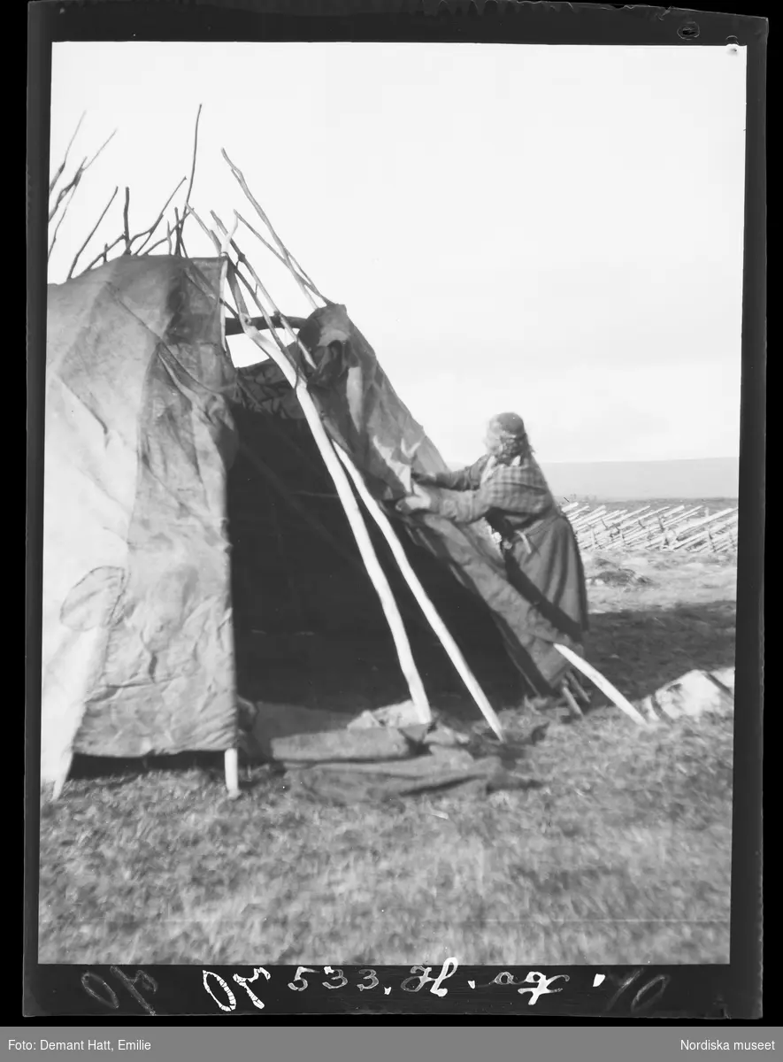 En kvinna, Siri (Sara Turi), sätter upp kåtan i Kattovuoma under vinterflytten 1907-1908. Troligen vid Laimo. Bilden ingår i en serie fotografier tagna av Emilie Demant Hatt i Sapmi mellan åren 1907 och 1916.