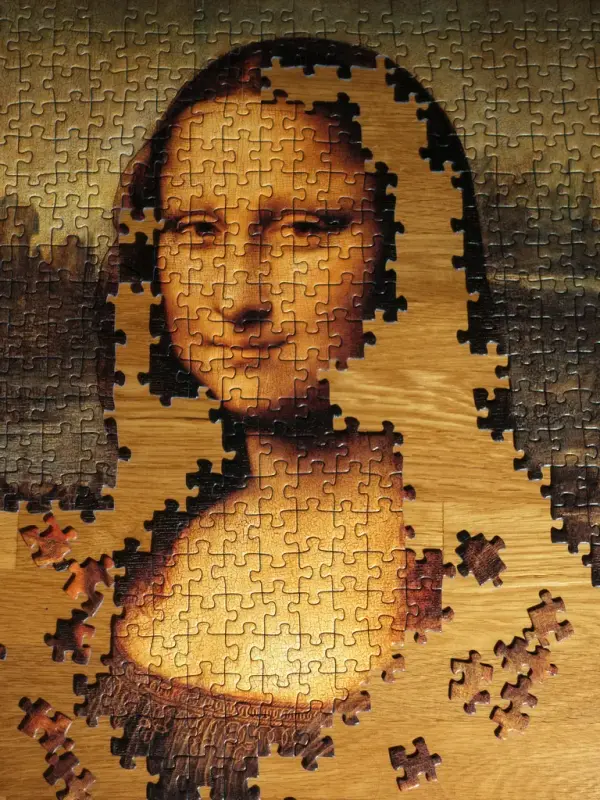 Stort bilde av et puslespill med Mona Lisa som motiv. Store deler av bildet er ennå ikke ferdig puslet, men du kan se at det er Mona Lisa.
