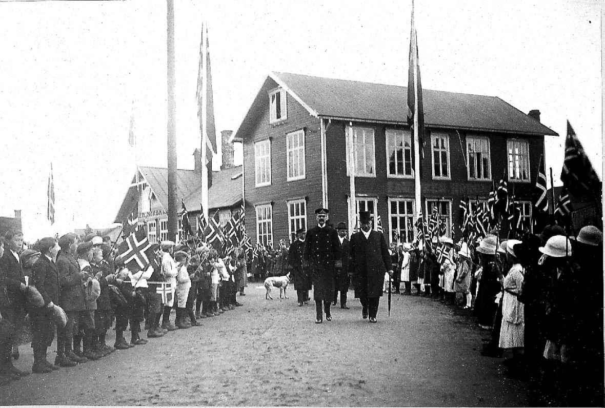 Kong Haakon og Christian Frederiksen spaserer oppover gatene på Melbu i 1922. i forbindelse med åpningen av Risøyrenna