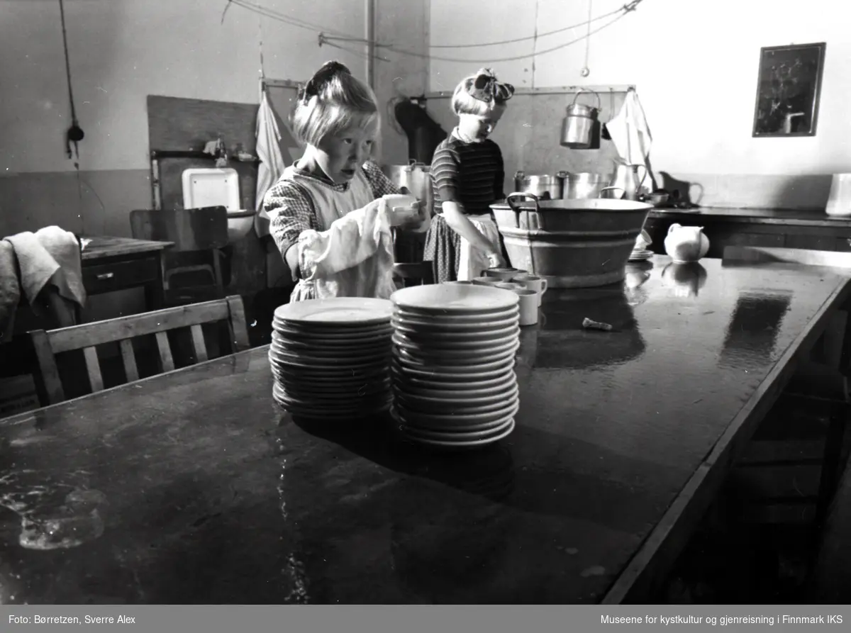 Skoleinternatet i Repvåg. Aud Severinsen (t.v.) og Solfrid Portvik vasker opp på kjøkkenet. Høsten 1952.