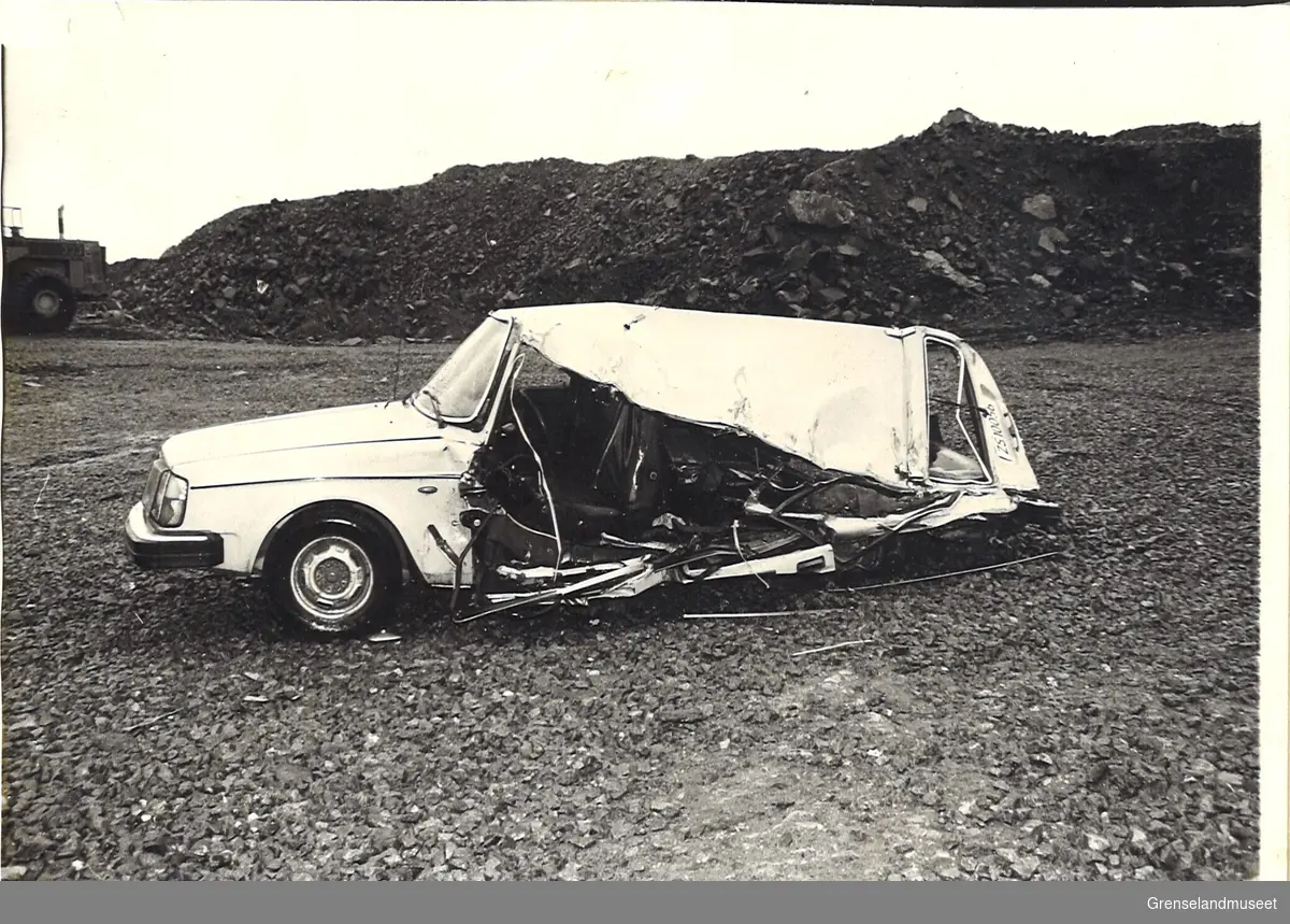 Trafikkulykke ved knuser 31.08.1983. Ulykkesstedet med skadet bil og dumper. Ulykkesbilen var en Volvo som ble påkjørt bakfra av en lastebil stor dumpere av typen Lectra Haul, som var en del av A/S Sydvaranger sin maskinpark. Skadene på bilden viser tydelig hvor lastebilens hjul har trykt ned på bilen bak mot front.