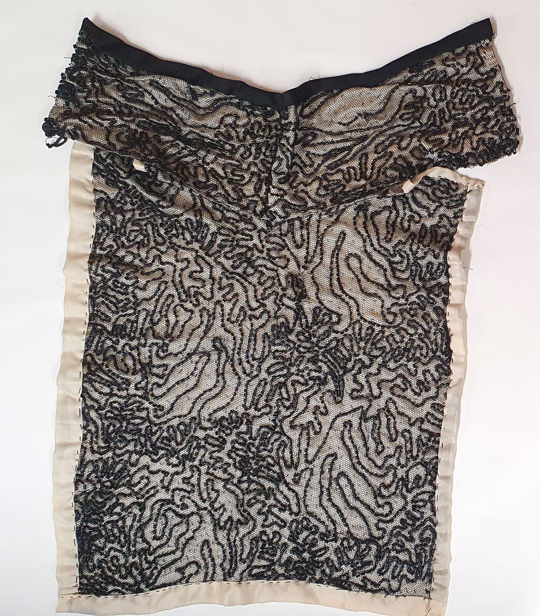 Løskrage eller kjolepynt av lys beige silke, påsydd svart tyll med sorte perlebroderi.