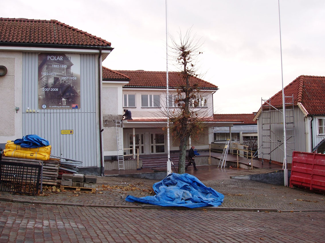 Renoveringsarbete av entré till Grenna Kulturgård från torget. På en vägg till vänster sitter en stor affisch för utställningen "Polarår!". Container och byggnadsmaterial i förgrunden.