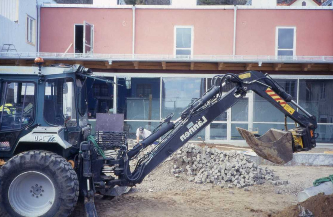 Traktor med grävskopa i arbete i kommande trädgård till Grenna Kulturgård som är under uppförande.