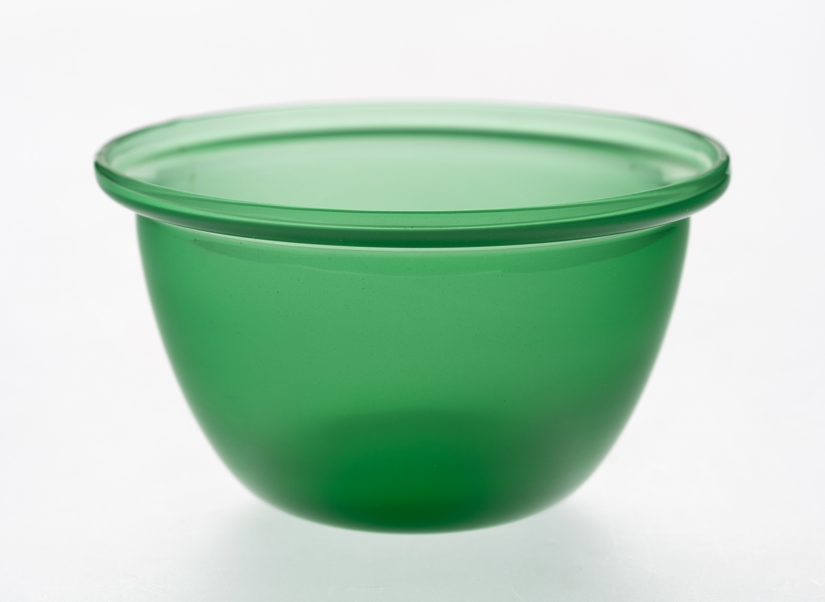 Tilnærmet halvkuleformet bolle, utført i halvgjennomskinnelig grønnfarget glass, med markert utoverbrettet munningsrand.