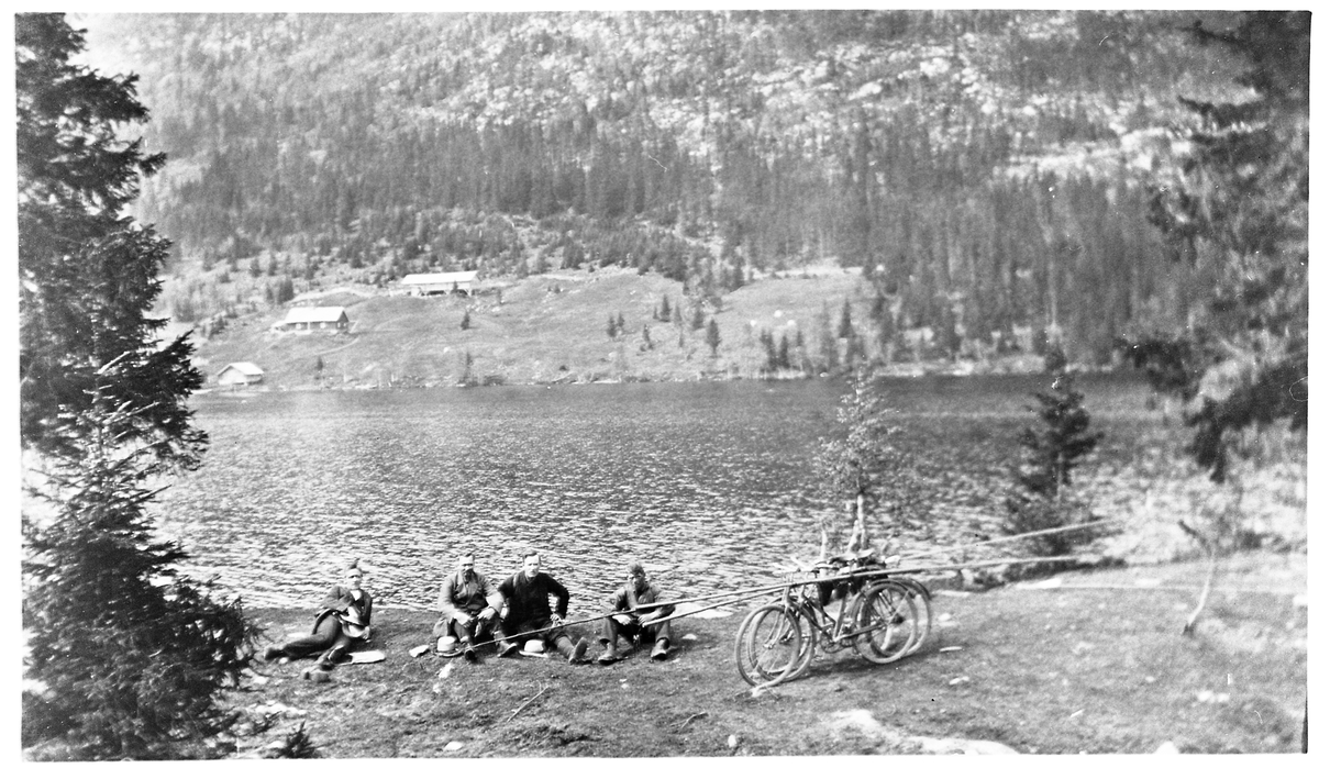 Skjeppsjøen på Totenåsen ca. 1920-21. Fire karer på fisketur sitter på bredden nærmest kamera. De er: Johannes Nergård, Bernt Johannessen, Ole Stenberg, og Wilhelm Lauritsen (feier).
På motsatt side er Holosætra.