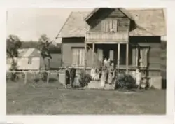 En gruppe mennesker, voksne og barn er oppstilt foran et hus
