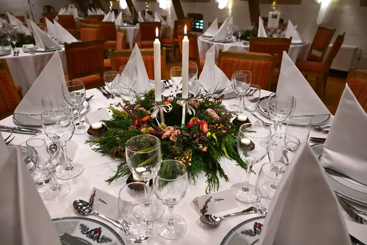 Bord dekket til selskap med julekrans og levende lys. 