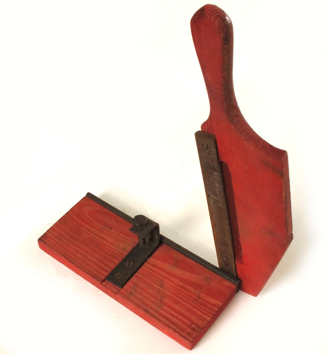 Skjæremaskin for tobakk,  fra krigen 1940-45.   
Furu,  rødmalt,   jernkniv.   
Kniv uten skarp egg. Form som en papirskjærer,  med håndtak/kniv langs den ene langside. Stilleskrue pm.  Tilstand: jernet rustent. Virker lite brukt.