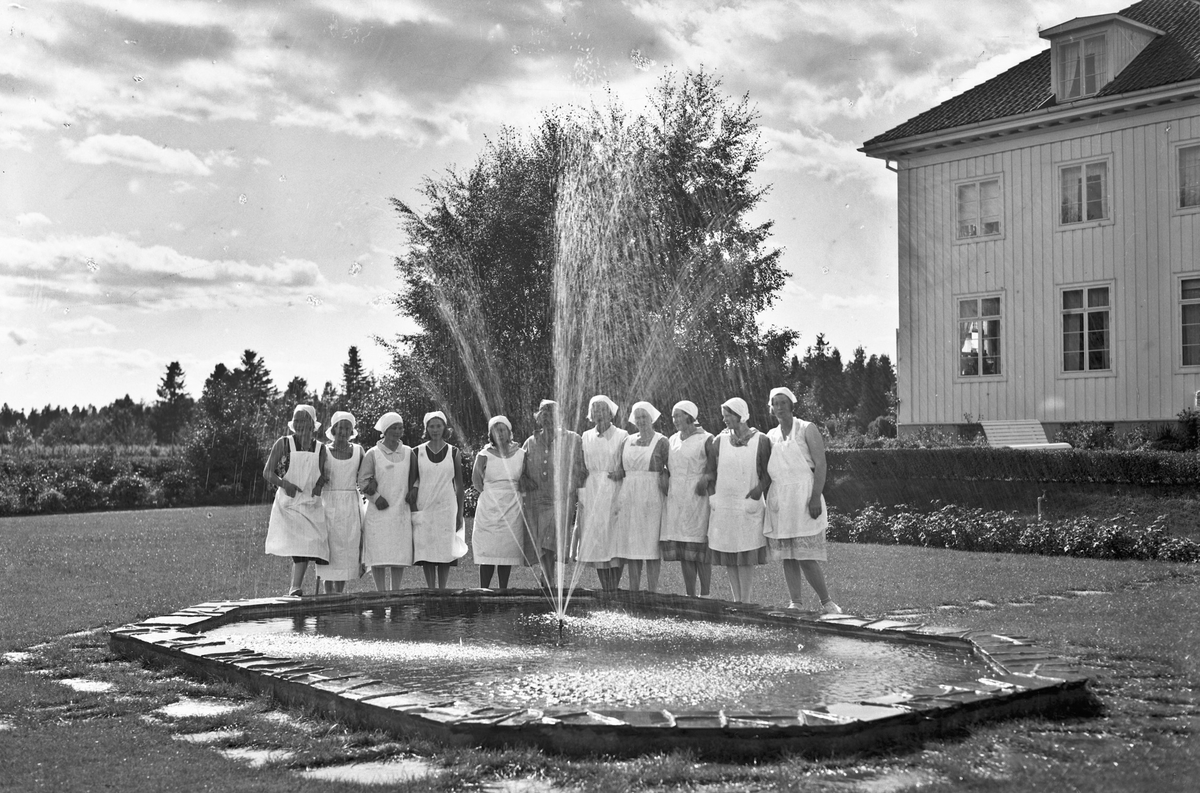 Kvinner i hvite uniformer utenfor Akershus Fylkes Husmorskole.