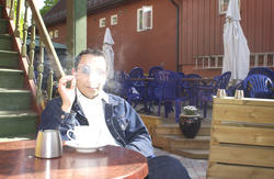 Pubgjest sitter ved et bord med røyk og kaffe i bakgården Mi