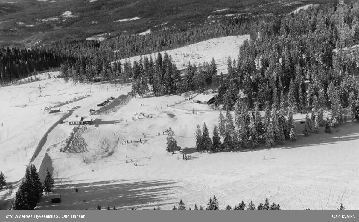Øvreseterveien, Tryvannsveien, Tomm Murstadbakken. Tomm Murstad skiskole og barnehage (Tommleplassen). En av Tryvannsmastene. (Vinter) (Flyfoto)
