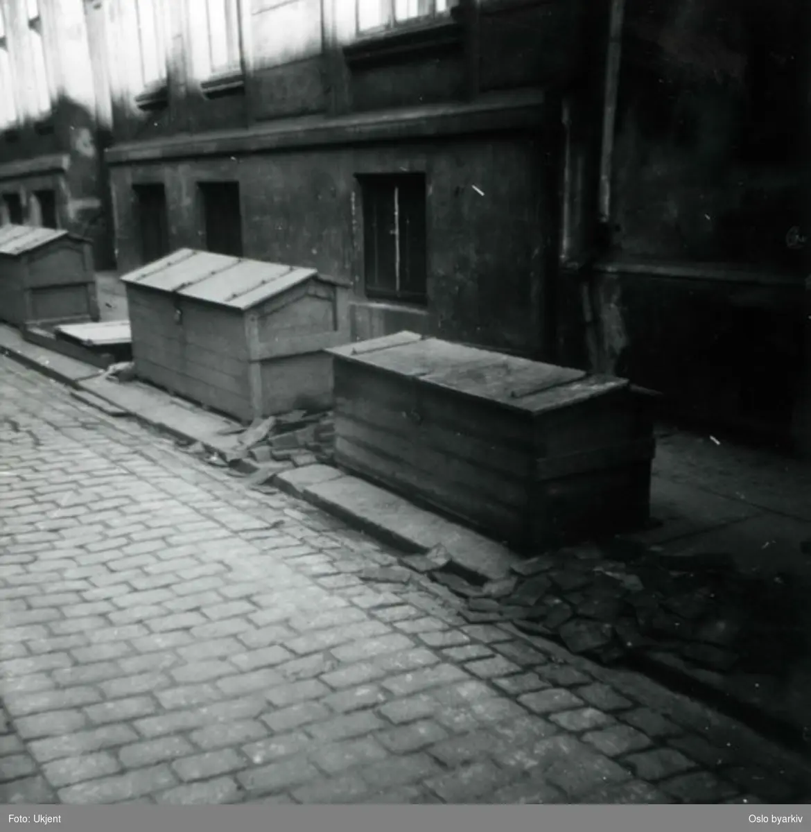 Redskapskasser eller kasser for oppbevaring av brostein langs brosteinsbelagt gate.