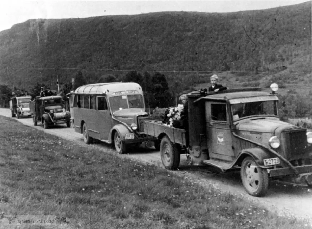 Bildet er tatt i forbindelse med Dorthea Malmedal (f. Øyen) sin begravelse i september 1945. Dorthea døde 6/9 1945. ..Lastebil med reg nr T-2723, Buss med reg nr T-4875 Dodge 1938 mod 24 sitteplasser, bygd av Røvik (90) og tilhørte Eide Auto..Lastebilen er en Chevrolet 1934-35 mod...Både i Hvem eier bilen 1939 og 1948 står T-2723 som Chevrolet lastebil, eier Øivind Holen, Elnesvågen. Siden alle bilene er utstyrt med gassgenerator for knottdrift i mangel av bensin, må bildet være tatt under eller umiddelbart etter krigen.