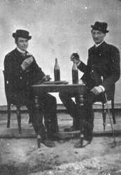 To ukjent menn. Flasker og glass på bord.