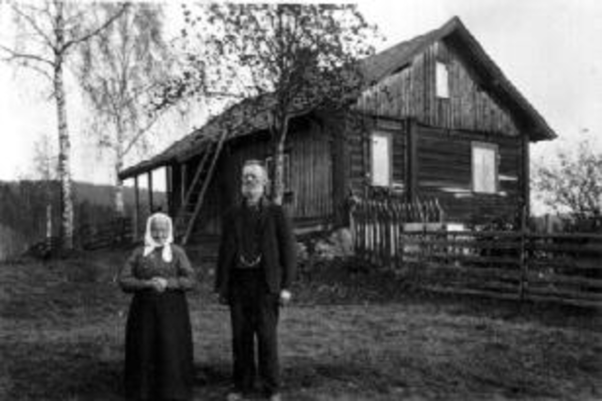Ektepar, Ole Evensen Bergelund f.1843 og hustru Kjerstine Johannesdatter  f.1842 foran boligen på plassen Bergelund under Mo gård, Ringsaker.