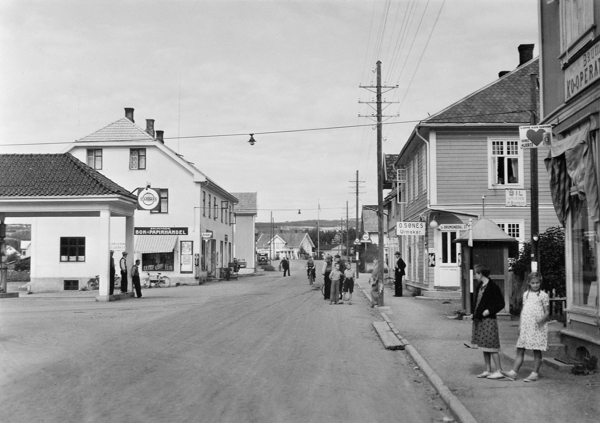 postkort-brumunddal-med-riksveg-50-gjennom-sentrum-standard-bensin