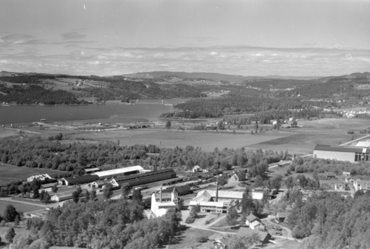 Flyfoto av Globus Maskinfabrikk, Brumunddal jernbanestasjon, potetmelfabrikken, Høyens Konfeksjonsfabrikk. Utsikt mot Veldre og Ringsaker.