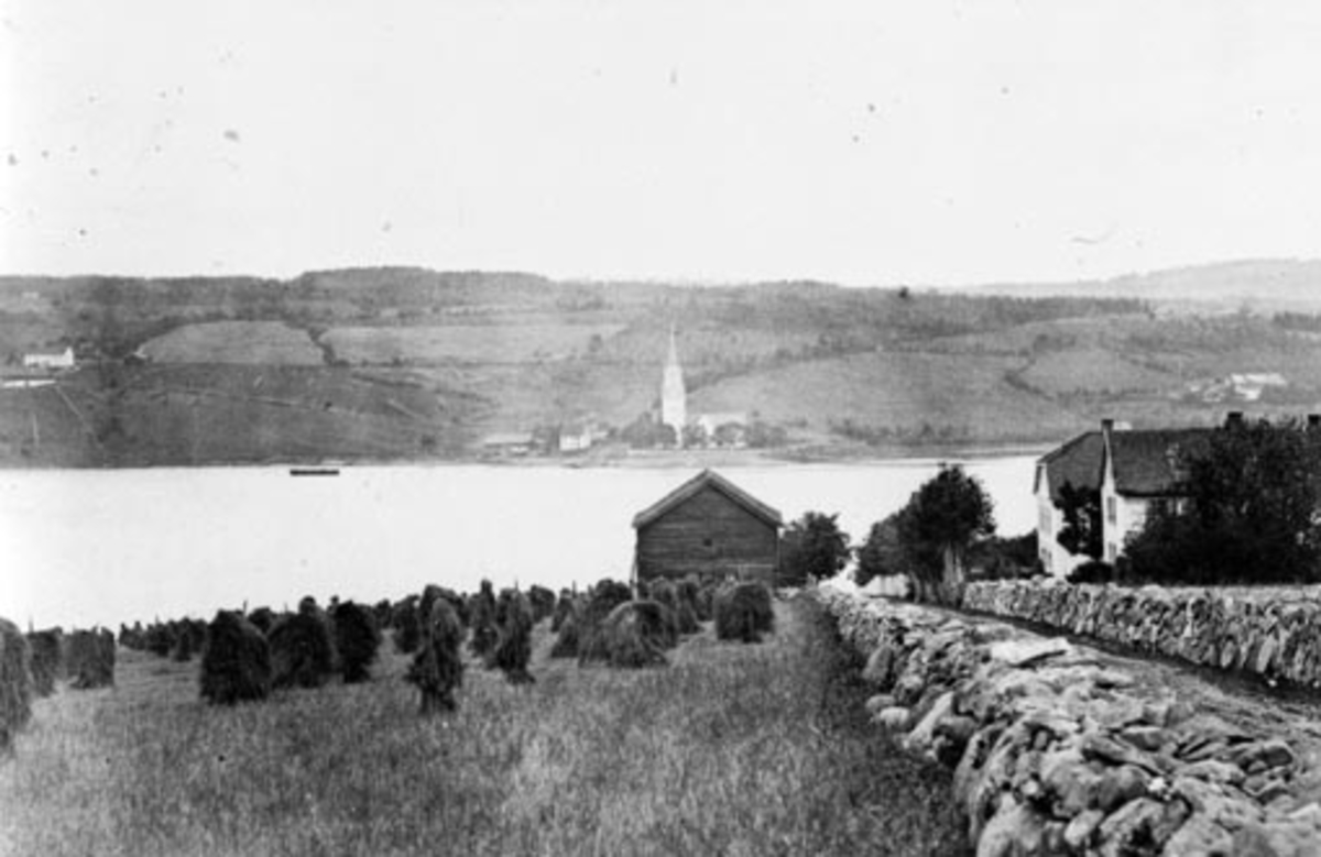 Steingjerder på Toftes Gave, Nedre Sund, Helgøya. Utsikt til Tingnes og Nes kirke. Kornband på staur (snes) til tørk.