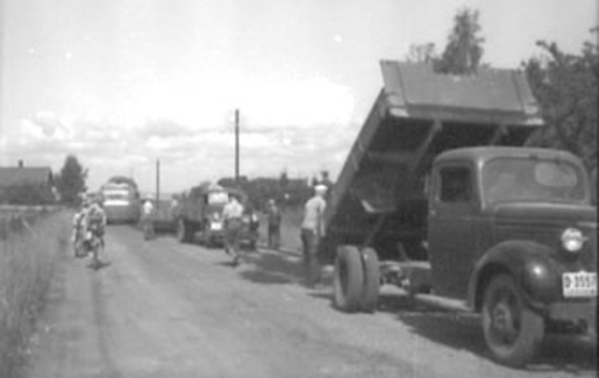 VEGARBEID, VEIARBEID, LEGGING AV ASFALT, MANGE BILER OG FOLK. Lastebiler, trolig begge Chevrolet, nærmest årsmodell 1939-40, så  1946-47.