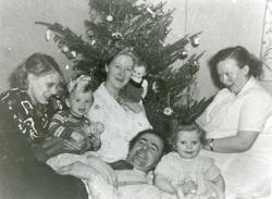 Fire voksne og to barn ved et juletre